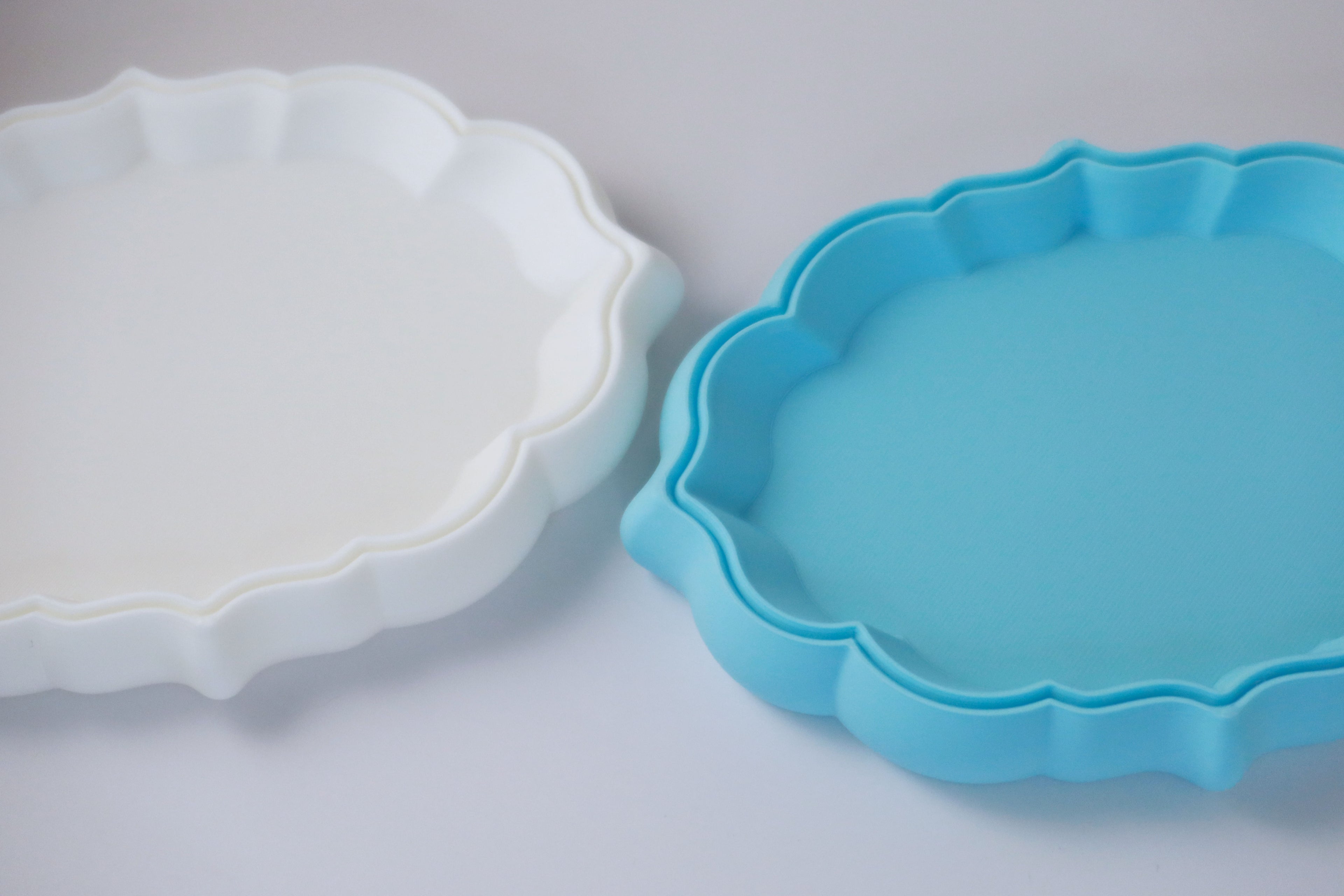 Two cloud-shaped trinket tray, one white and one blue, on a light gray background.