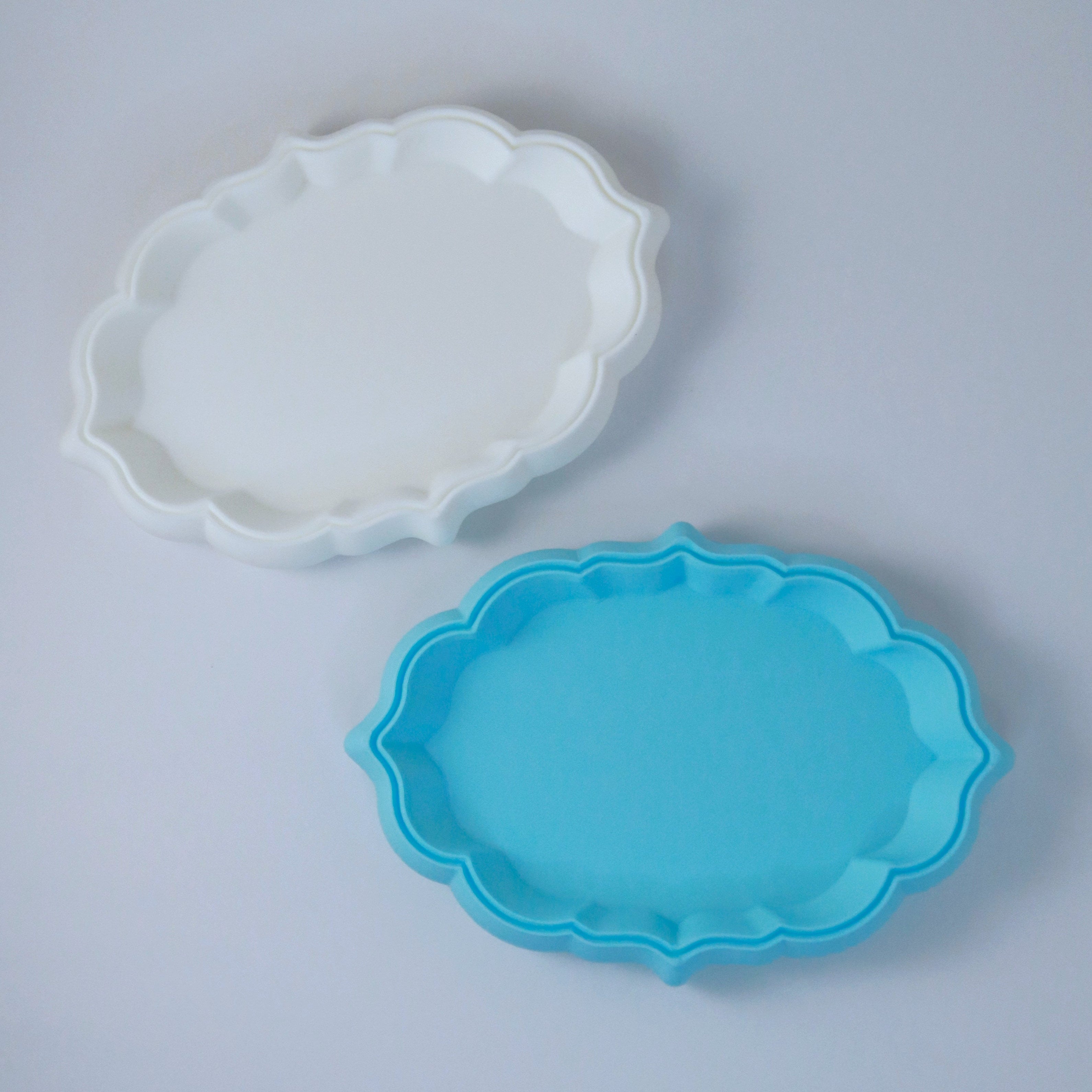 Two cloud shaped trays, one white and one blue, on a light gray background.