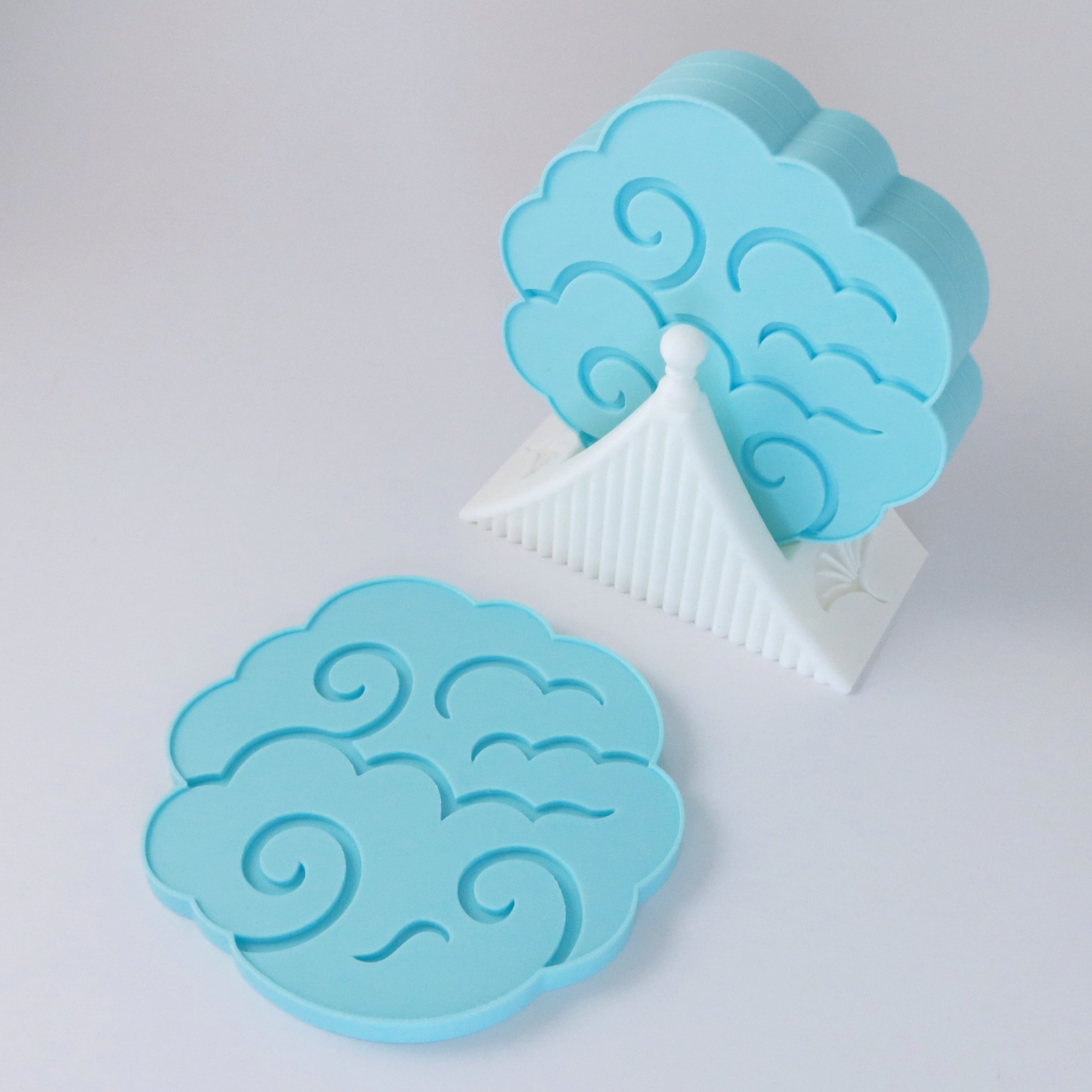 Blue cloud-shaped coasters on a light gray background