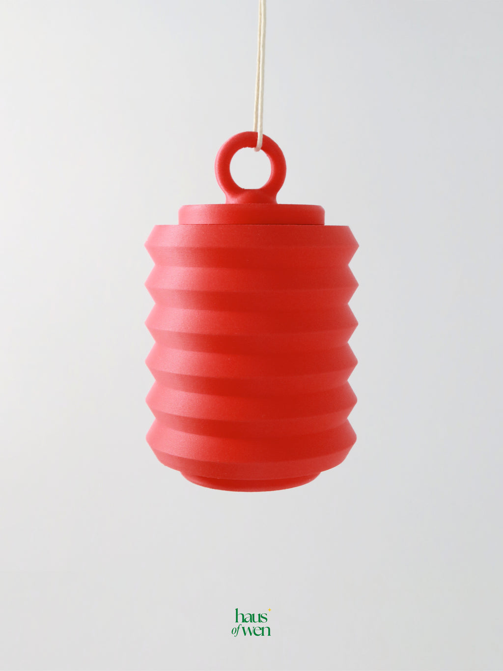 Red lantern ornament hanging against a light gray background with "haus of wen" branding